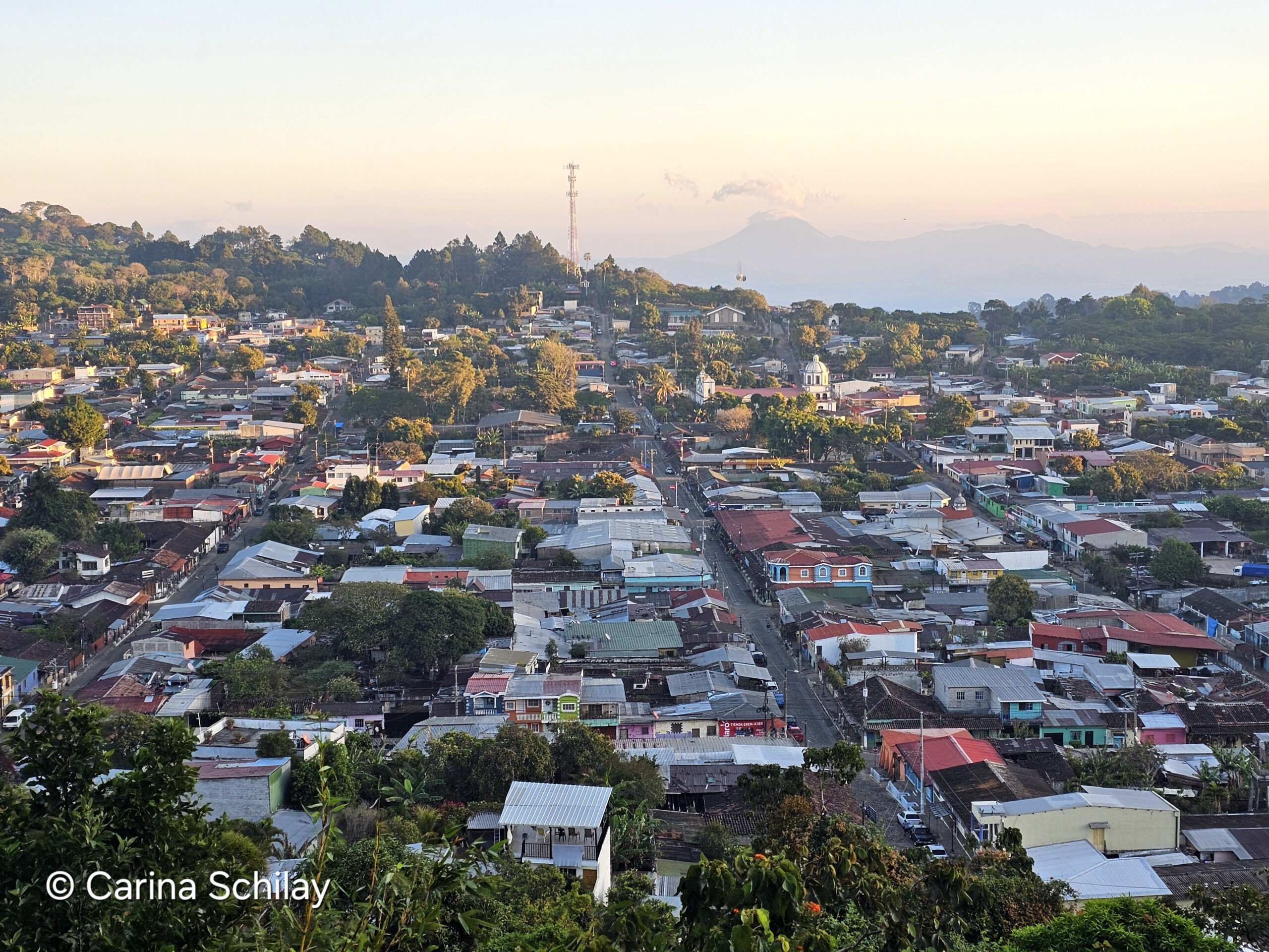 Malerischer Sonnenaufgang über Apaneca, El Salvador, mit einem Blick auf die roten Dächer der Stadt und die sanften Hügel im Hintergrund.