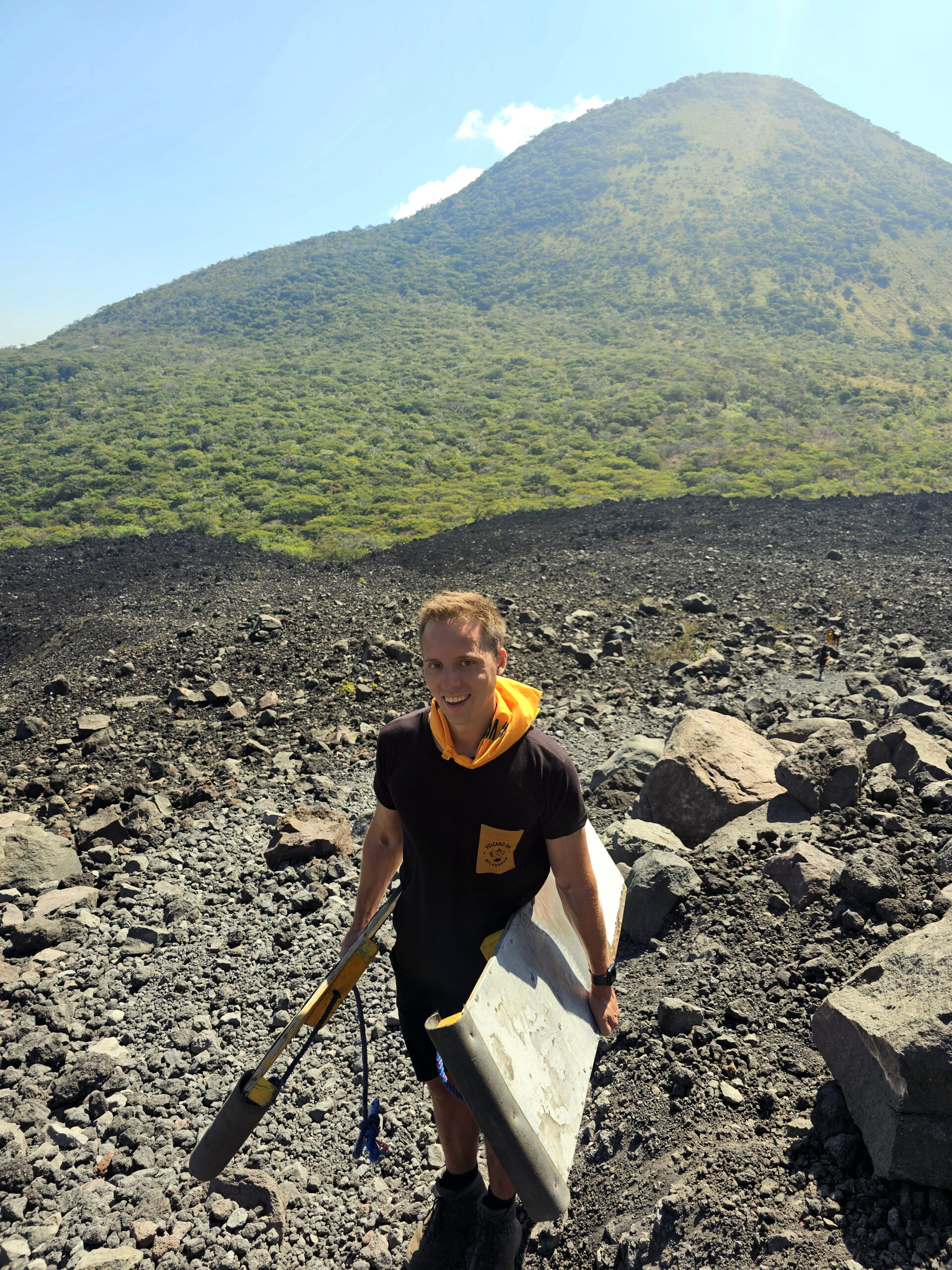 Ein Abenteurer trägt zwei Sandboards den Cerro Negro hinauf,