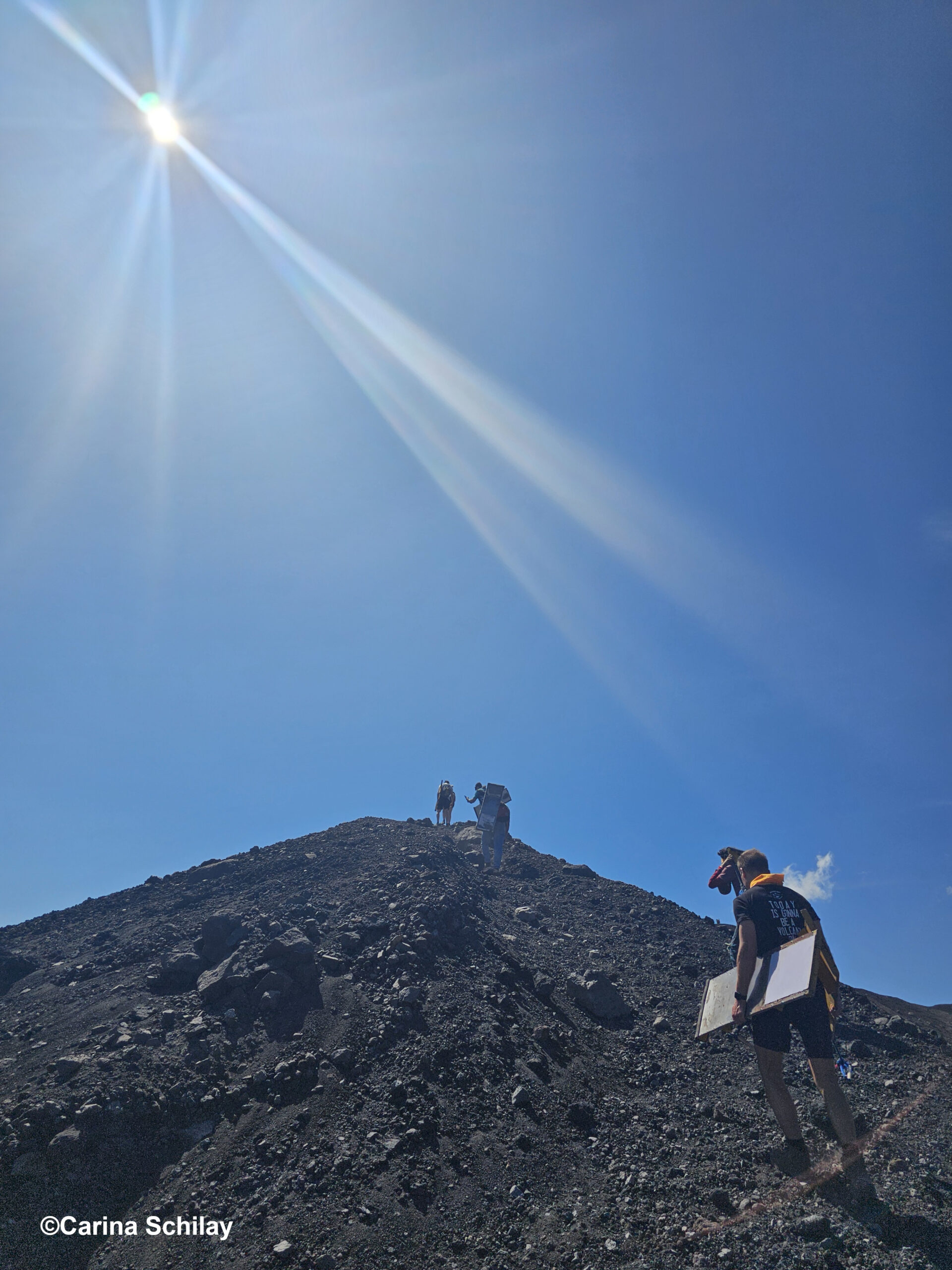 Abenteuerlustige Person steht mit einem Sandboard am Fuße des Cerro Negro unter der strahlenden Sonne Nicaraguas.