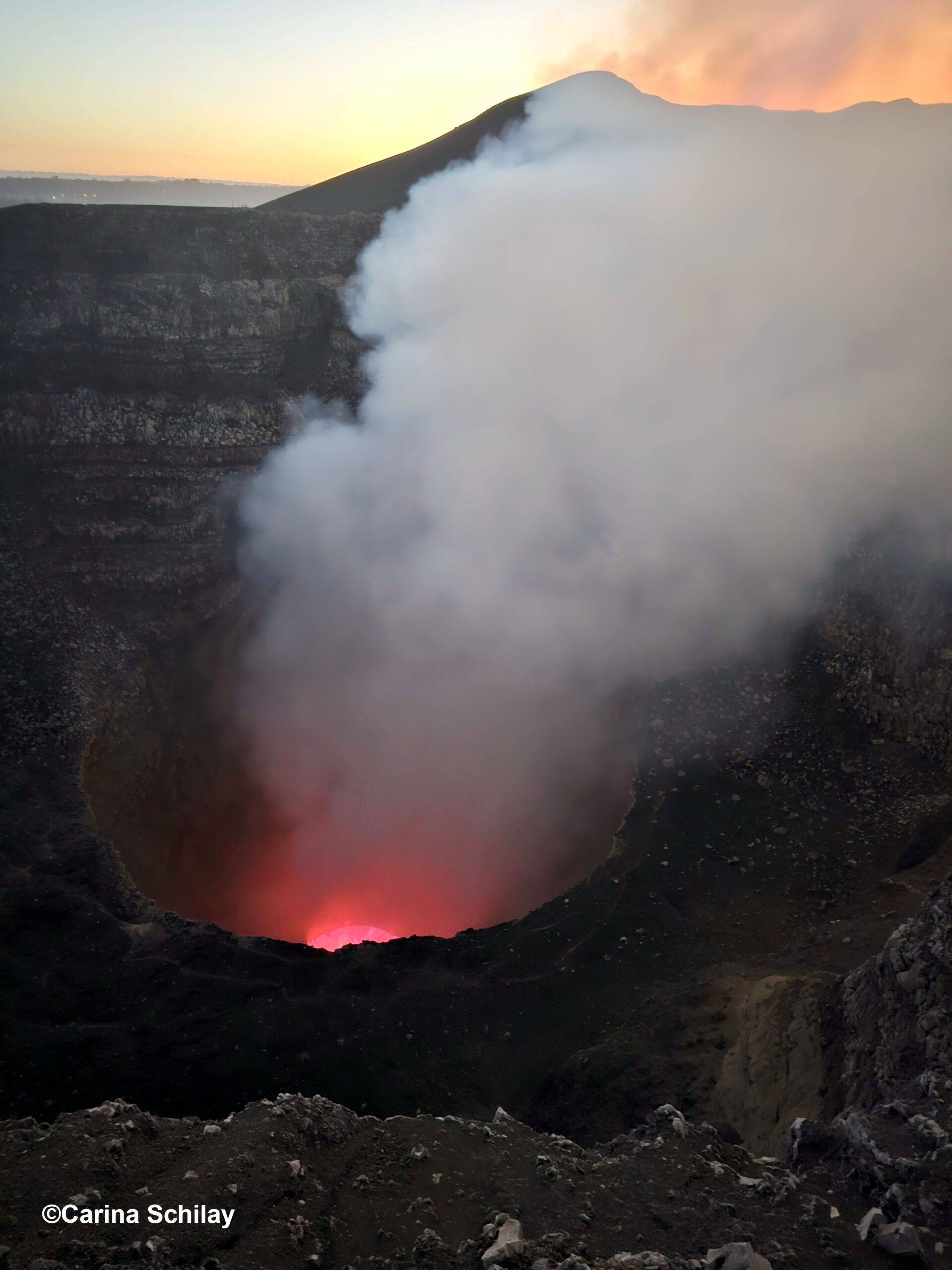 Blick in den rauchenden Krater des Masaya Vulkans bei Sonnenuntergang mit sichtbarem Lavasee.