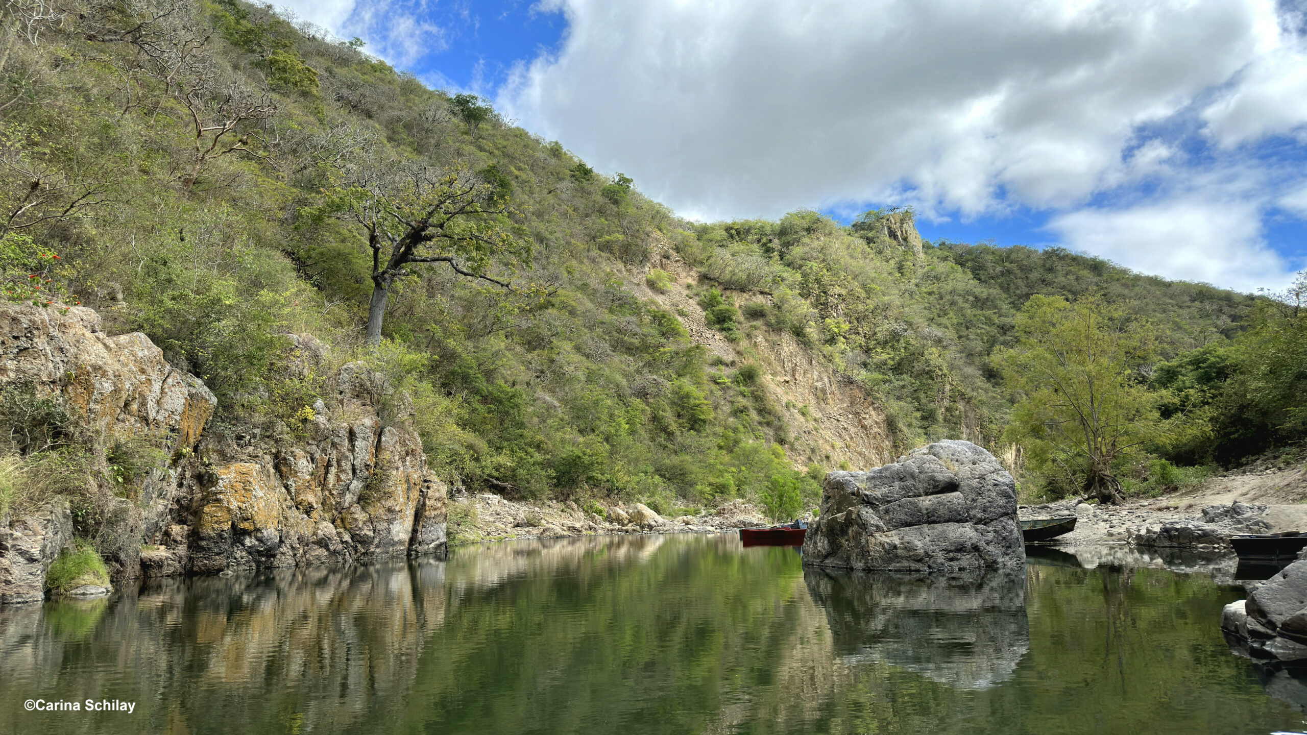 Ufer des Rio Coco mit mehreren Booten, bereit für die Überfahrt, umgeben von steilen Felswänden und dichter Vegetation.